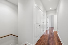 A long hallway with white walls and wood floors.