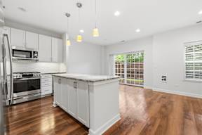 A kitchen with white cabinets and a wooden floor.