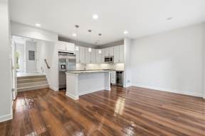 A kitchen with white cabinets and a wooden floor.