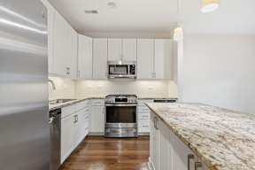 A kitchen with white cabinets and a granite counter.