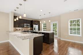 A kitchen with a marble countertop and dark brown cabinets.