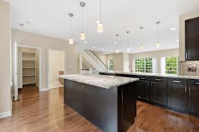 A kitchen with a marble countertop and wooden floors.
