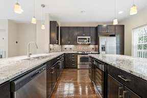 A modern kitchen with dark wood cabinets and stainless steel appliances.