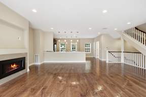 A spacious living room with a fireplace and wooden floors.