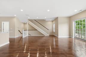 A spacious room with wooden floors and a staircase.