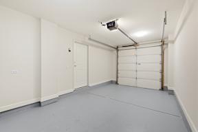 A spacious garage with a white door and a grey floor.