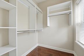 A room with white shelves and a window with blinds.