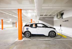 A white electric car is charging in a parking garage.
