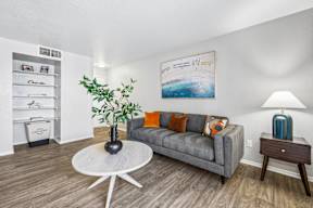 A living room with a grey couch, a white coffee table, and a painting on the wall.