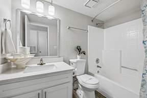 A white bathroom with a toilet, sink, and mirror.