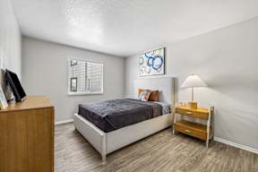 A bedroom with a bed, nightstand, and a painting on the wall.