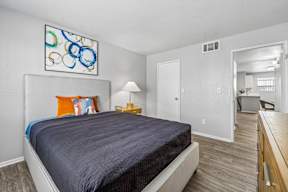 A bedroom with a bed, a lamp, and a painting on the wall.