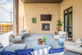 A patio with a fireplace, chairs, and a table with a plant on it.