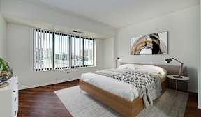 A bedroom with a large bed and a painting on the wall.