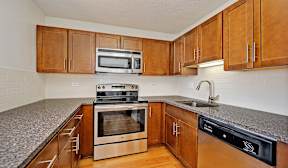 A kitchen with wooden cabinets and a granite countertop.