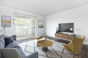 A living room with a grey couch, a yellow chair, a coffee table, and a television.