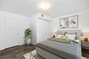 A bedroom with a bed, nightstands, and a plant.