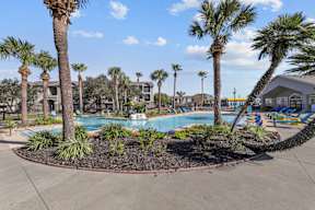 A pool surrounded by palm trees and plants.