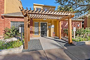 a covered walkway in front of a brick building with a door