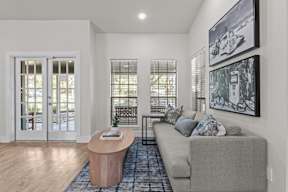 A living room with a grey couch, a wooden table, and a painting on the wall.