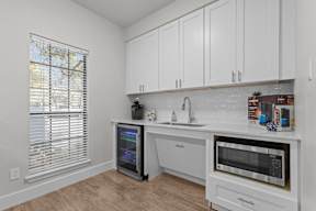 A kitchen with white cabinets and a black fridge.