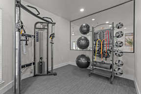 A gym with a variety of equipment including a squat rack, a leg press machine, and a medicine ball.
