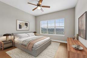 A bedroom with a bed, nightstand, and a ceiling fan.