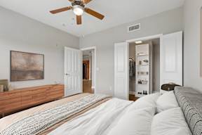 A bedroom with a large bed and a ceiling fan.