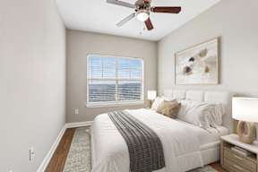 A bedroom with a bed, nightstand, and a ceiling fan.