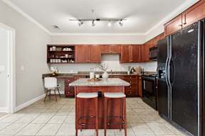 A kitchen with a black refrigerator and wooden cabinets.