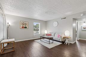 A living room with a white couch, a wooden coffee table, and a painting on the wall.