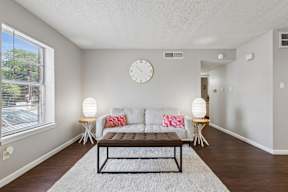 A living room with a couch, a table, and a clock on the wall.
