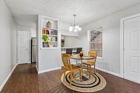 A dining room with a table set for two and a bookshelf filled with books.