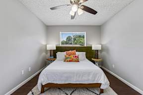 A bedroom with a bed, two lamps, and a ceiling fan.