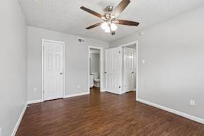 A room with a ceiling fan and wooden floors.