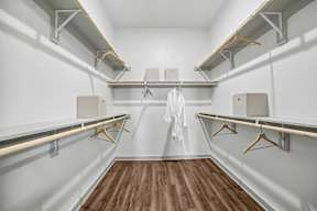 A walk-in closet with wooden floors and white walls.