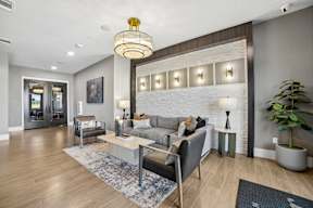 A modern living room with a grey couch, a coffee table, and a large chandelier.