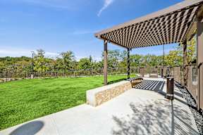 A patio with a pergola and a concrete walkway.