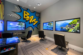a large gaming room with three monitors and a boom sign