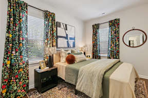 A bedroom with a bed, a nightstand, and a mirror.