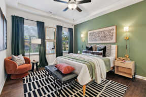 A bedroom with a bed, chair, and rug.