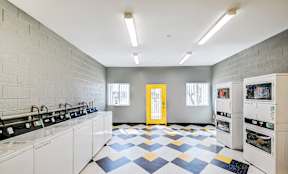A laundry room with a checkered floor and a yellow door.