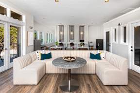 a living room with a large white couch and a round table with a bowl of fruit on