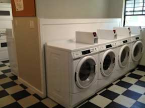 A row of white front load washing machines in a laundromat.