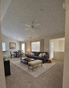 A living room with a grey couch, a coffee table, and a ceiling fan.