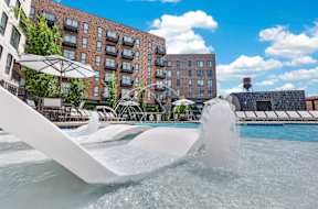 A fountain in the middle of a pool with a building in the background.