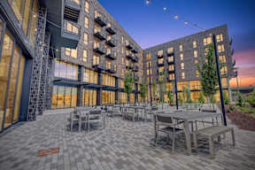 A modern building with a patio and tables.