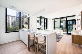 A kitchen with white countertops and wooden floors.