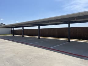 an empty parking lot with awning in front of a building