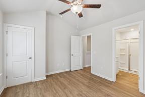 A room with a ceiling fan and wooden floors.